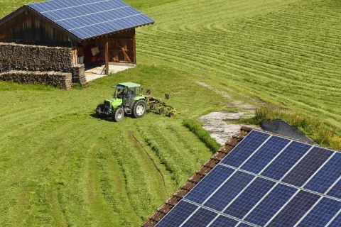 Eine Solaranlage auf einer Scheune mit Traktor davor.